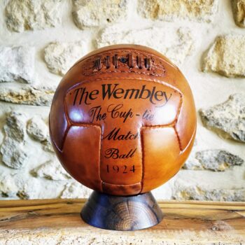 Ballon de football vintage en cuir patiné, reproduction fidèle du modèle Wembley 1924, cousu main et présenté sur un socle en bois artisanal. Objet de collection unique pour les passionnés de football, la décoration sportive ou les amateurs d’objets anciens. Parfait pour une mise en valeur authentique et élégante dans un intérieur au style vintage.