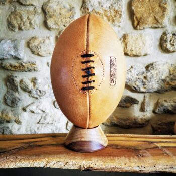 Détail du ballon de rugby en cuir crème, cousu main et vieilli naturellement sans patine artificielle. La couture visible témoigne du travail artisanal Ben & Flo, basé en France. Chaque panneau est retourné à la main pour dissimuler les coutures internes. Sa couleur claire et son aspect mat évoluent subtilement avec la lumière, faisant de chaque pièce un ballon unique et intemporel.