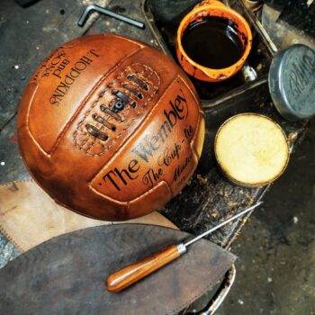 gros plan sur ballon de foot ancien cuir avec patine miel et coutures apparentes