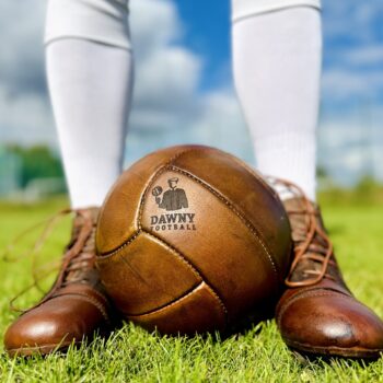 Ballon de foot vintage Dawny dans les pieds d'un joueur sur le terrain.
