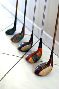 Set of old wood shaft steel golf clubs against a wall