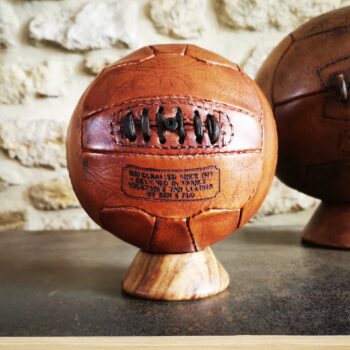 Mini ballon de football vintage en cuir, couleur miel, fabriqué artisanalement, posé sur un socle en bois.