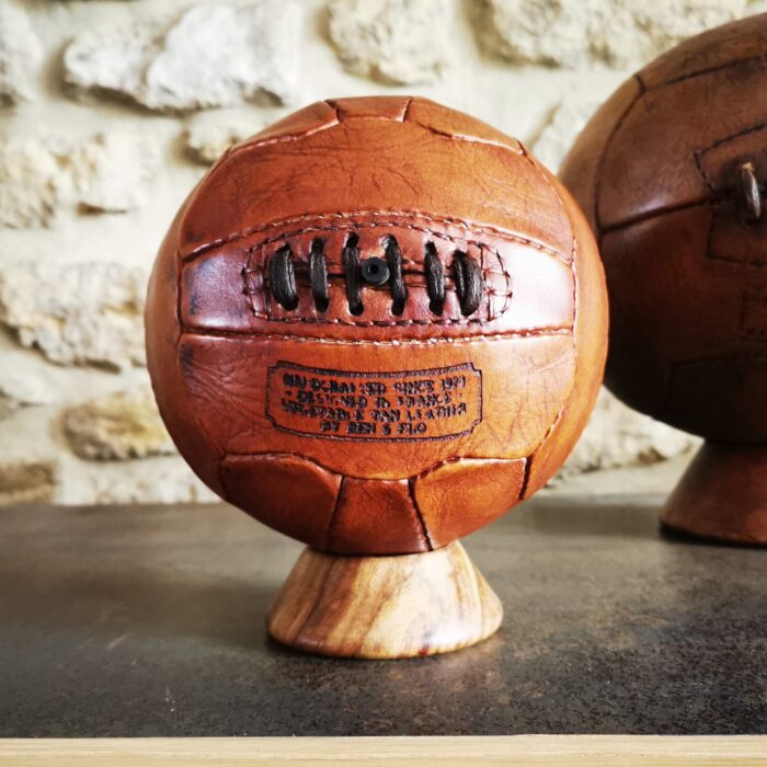 Mini ballon de football vintage en cuir, couleur miel, fabriqué artisanalement, posé sur un socle en bois.