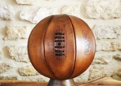 Ballon de basket en cuir vintage couleur miel exposé sur socle en bois massif