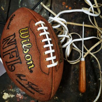 Ballon de football américain Wilson en réparation, avec passe-lacet et lacets en cuir blanc. Idéal pour illustrer la réparation d’un ballon vintage avec lacet américain authentique.