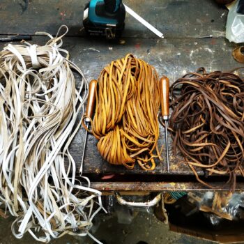 Lot de lacets en cuir naturel Ben & Flo dans trois teintes (blanc, camel miel et brun foncé), posés sur un établi d’atelier. Ces lacets sont utilisés pour réparer ou personnaliser les ballons de football américain NFL ou vintage. Produit artisanal issu de l’atelier Ben & Flo en France, symbole de durabilité et de savoir-faire sportif traditionnel.