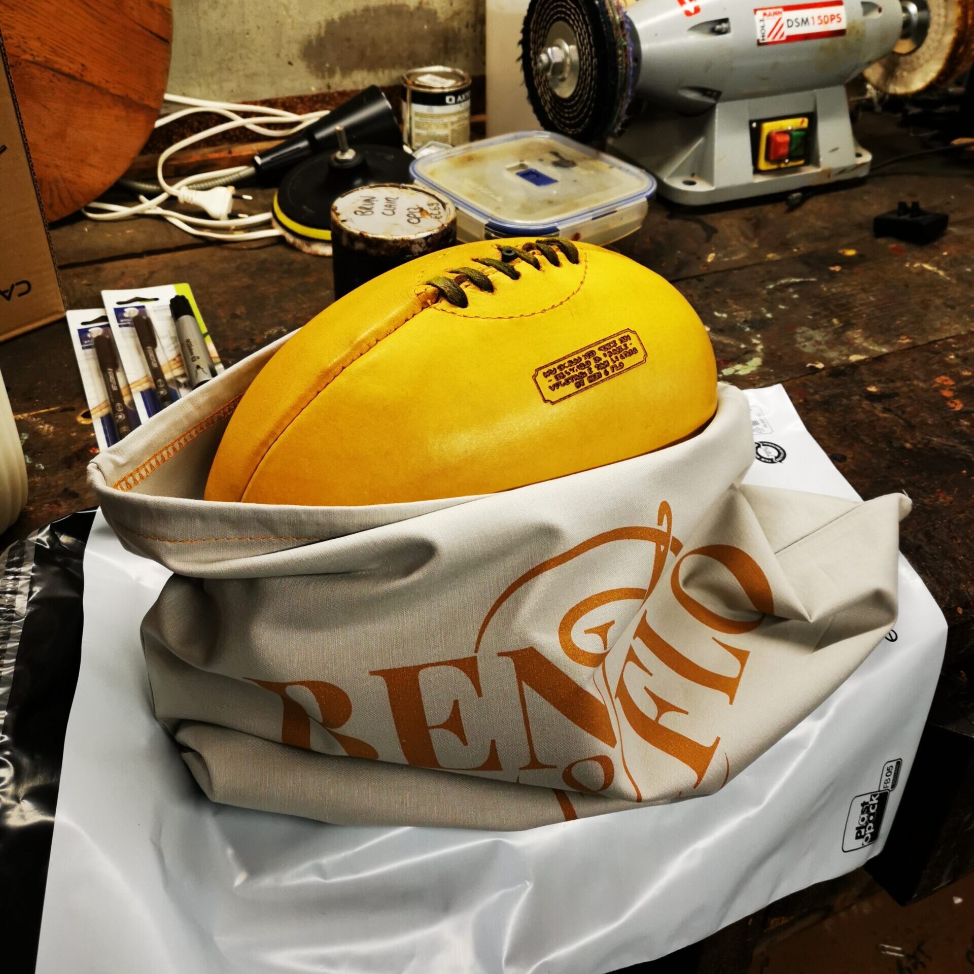 Ballon de rugby vintage en cuir jaune posé dans un sac en coton Ben et Flo