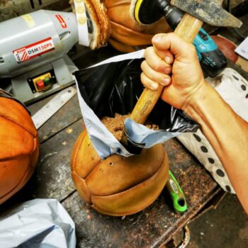 Remplissage manuel d’un médecine ball en cuir avec sable et tissu
