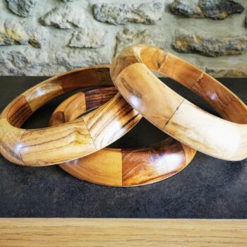 Support design pour ballon de gym, associant acacia doré et bois de rose foncé, fabriqué en France.