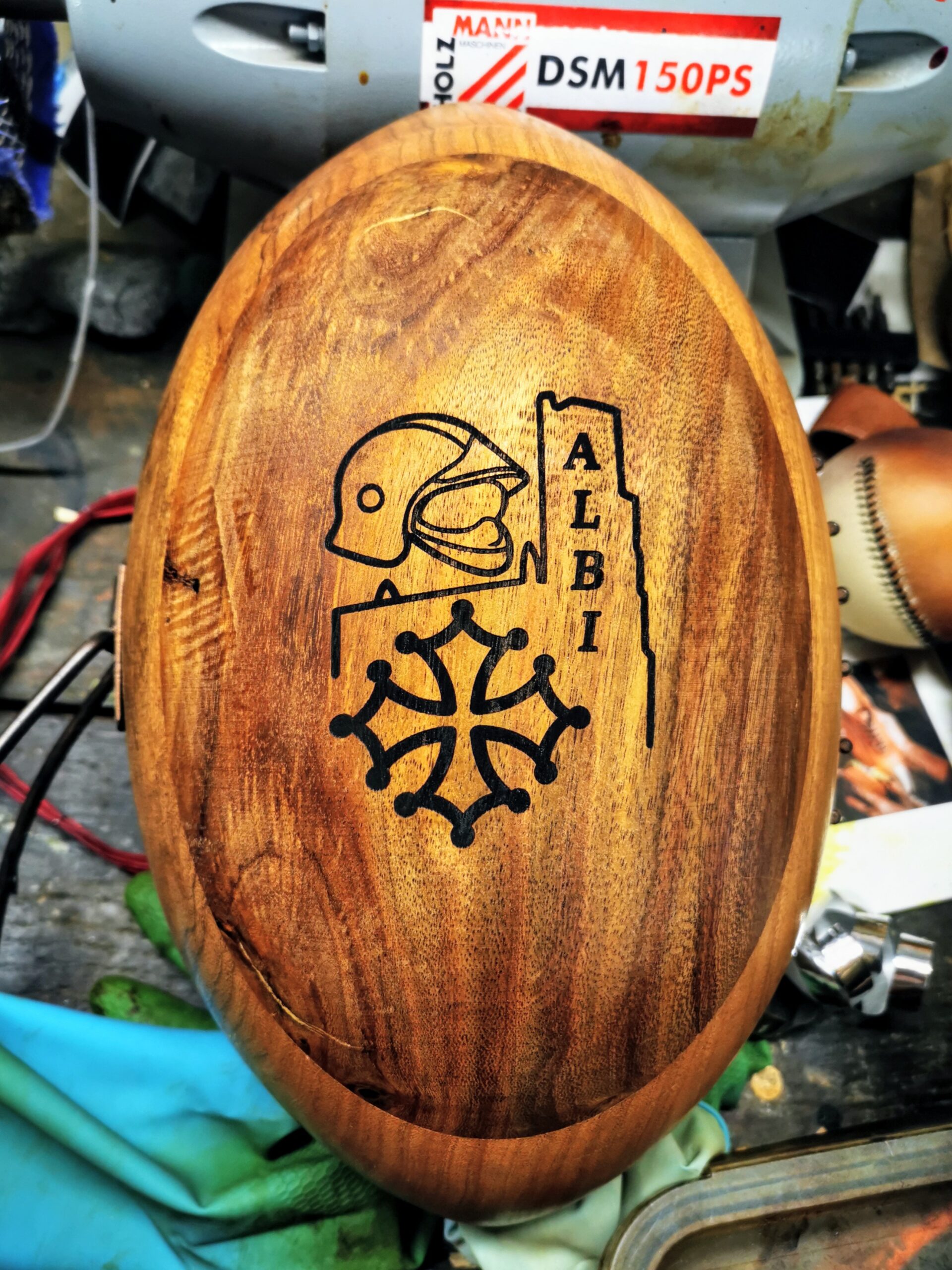 Ballon de rugby en bois massif sculpté à la main, gravé au laser avec un blason et un logo de club de rugby. Objet décoratif haut de gamme pensé comme idée cadeau pour clubs de rugby, dirigeants, bénévoles ou partenaires. Ballon en bois naturel avec veinage apparent, finition artisanale, idéal pour trophée, cadeau de fin de saison ou décoration de club house.