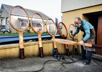 plusieurs raquettes de tennis géantes en bois alignées décoration tennis club