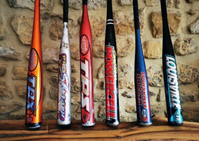 Collection de battes de baseball vintage en aluminium posées contre un mur en pierre, parfait pour décoration sport vintage