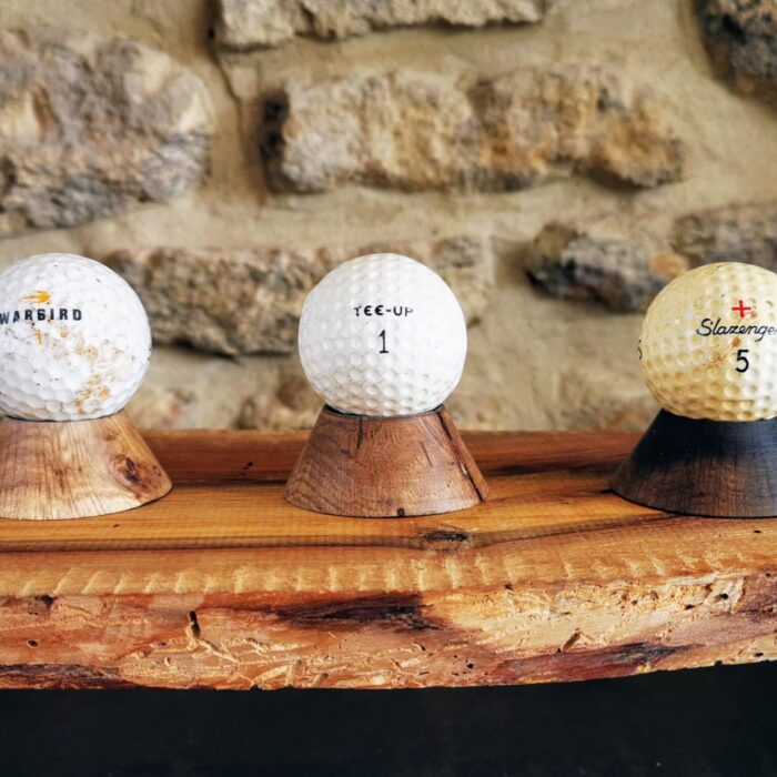 Plusieurs balles de golf posées sur des minis socles en chêne