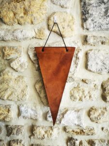 Fanion en cuir personnalisé minimaliste suspendu sur un mur en pierre